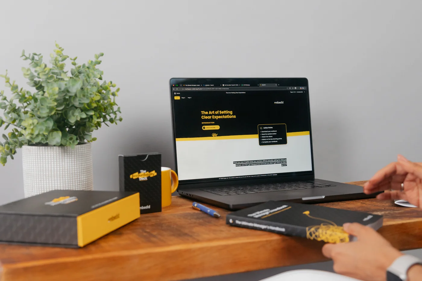 An embed’d online course on a laptop beside the accountability toolbox and manager’s handbook